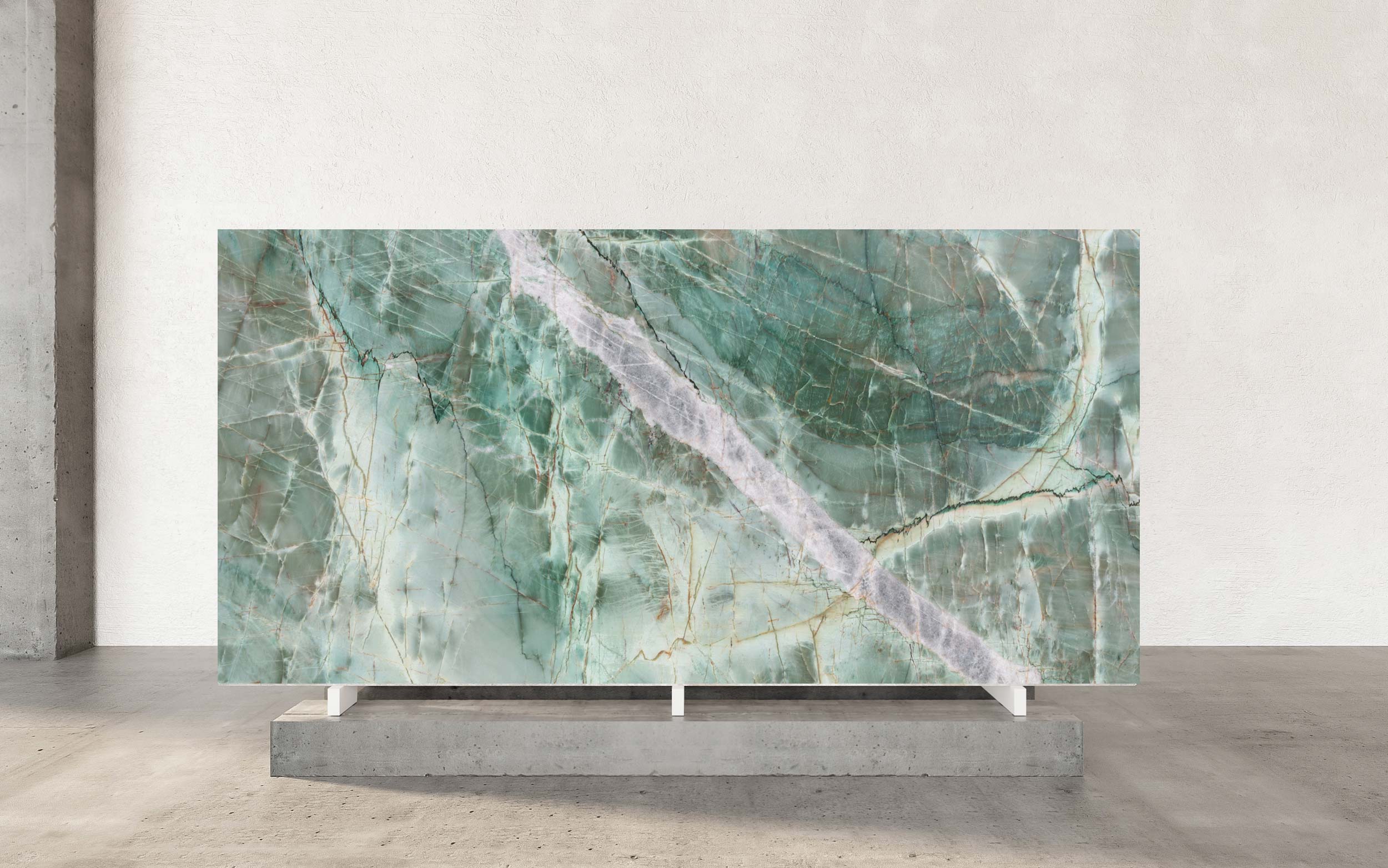 Jadore Quartzite distinguishes itself with a serene green base that transitions elegantly into delicate shades of grey, creating a refined, organic palette. Across this tranquil surface, a constellation of diagonal soft grey veins interlaces with one especially prominent vein, sweeping boldly through the stone. This larger movement serves as the composition’s visual anchor—an elegant gesture that draws the eye and showcases the dynamic artistry found only in nature. Subtle crystalline deposits are scattered throughout, reflecting light in a manner that imparts gentle depth and sophistication. This harmonious interplay of form and color is matched by Jadore Quartzite’s exceptional durability, making it a preferred choice for projects defined by distinction. The stone’s poised beauty comes to life in luxurious applications, from statement countertops and refined flooring to dramatic wall cladding, where the interplay of green, grey, and that singular bold vein can be fully appreciated. For interiors that value both heritage and forward-thinking design, Jadore Quartzite offers a foundation of enduring quality, artistic movement, and quiet prestige.