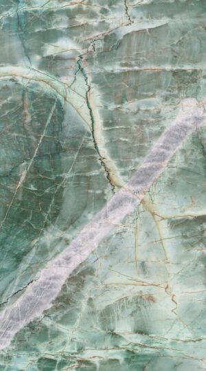 Jadore Quartzite distinguishes itself with a serene green base that transitions elegantly into delicate shades of grey, creating a refined, organic palette. Across this tranquil surface, a constellation of diagonal soft grey veins interlaces with one especially prominent vein, sweeping boldly through the stone. This larger movement serves as the composition’s visual anchor—an elegant gesture that draws the eye and showcases the dynamic artistry found only in nature. Subtle crystalline deposits are scattered throughout, reflecting light in a manner that imparts gentle depth and sophistication. This harmonious interplay of form and color is matched by Jadore Quartzite’s exceptional durability, making it a preferred choice for projects defined by distinction. The stone’s poised beauty comes to life in luxurious applications, from statement countertops and refined flooring to dramatic wall cladding, where the interplay of green, grey, and that singular bold vein can be fully appreciated. For interiors that value both heritage and forward-thinking design, Jadore Quartzite offers a foundation of enduring quality, artistic movement, and quiet prestige.