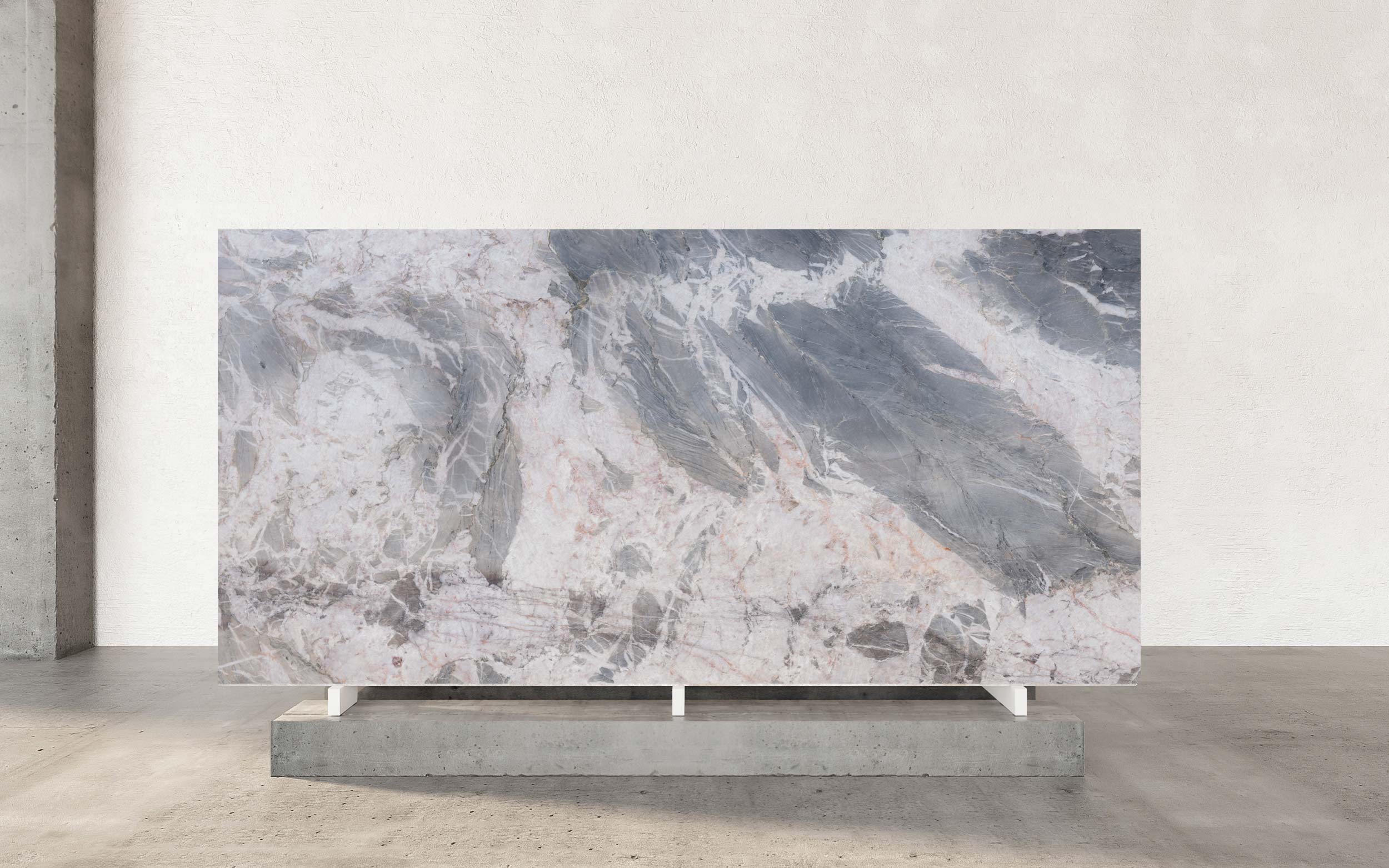 Monte Azul Polished Quartzite presents a refined and elegant composition, a testament to nature's subtle yet powerful artistry. Its polished surface enhances a sophisticated grey base, which transitions with graceful fluidity from deep, shadowy charcoal to soft, misty silver. Scattered across this serene landscape are distinct bodies of pure white, like clouds drifting across a twilight sky, providing moments of bright contrast and visual intrigue. This interplay of light and dark creates a balanced and harmonious aesthetic, offering a foundation of quiet luxury for any distinguished interior space. The true character of Monte Azul is revealed in its details. Along the periphery of the main color fields, intricate, thinner veins emerge in a complex and delicate network, adding a layer of remarkable intricacy to the stone's overall appearance. This fine veining provides a subtle counterpoint to the broad sweeps of grey and white, showcasing the material's geological story. Ideal for expansive countertops, graceful wall cladding, or sophisticated fireplace, Monte Azul Polished Quartzite delivers a timeless and elegant statement, backed by the enduring strength and quality inherent to natural quartzite.